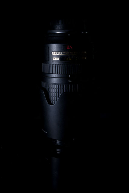 Low key photo of a camera lens, where a piece of polystrene was used to block the light from hitting the background.