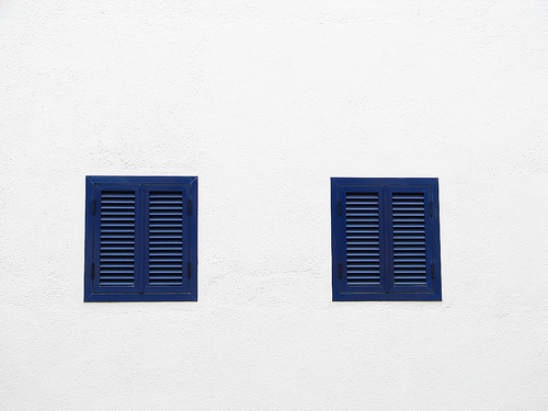 Bull shuttered windows on white wall architectural detail