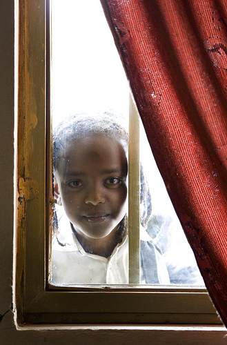 Girl framed by window and curtain