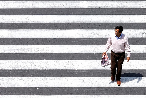 High angle photo of man crossing a pedestrian crossing