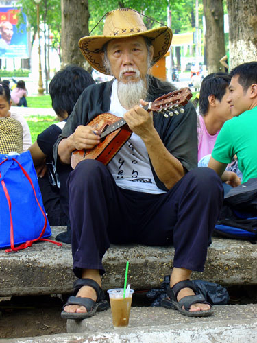 Friendly man playing Mandolin in the park near Notre Dame Cathedral, Ho Chi Minh City, Vietnam