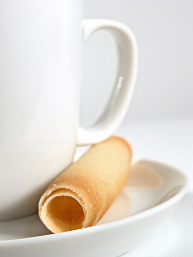 Stock Photo of a biscuit resting next to a cup in a saucer