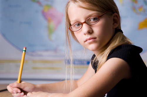 Stock Photo of a young girl writing with a pencil in a classroom setting