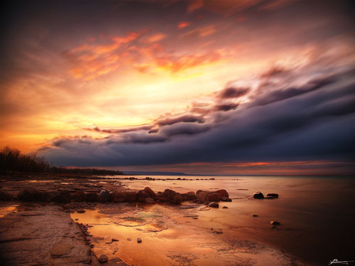 Orange sunset colors in the sky and reflected on a wet beach