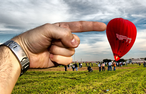 Forced perspective photo of a giant hand pushing a hot air balloon