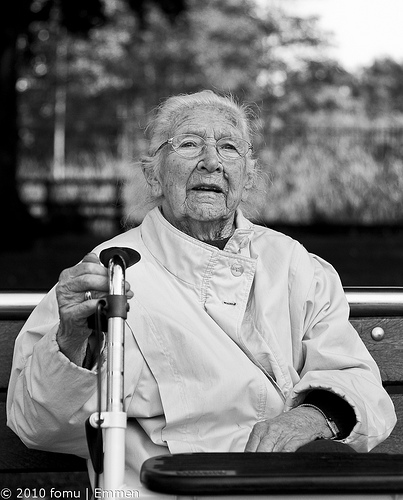 Black & white street photo of an elderly woman resting