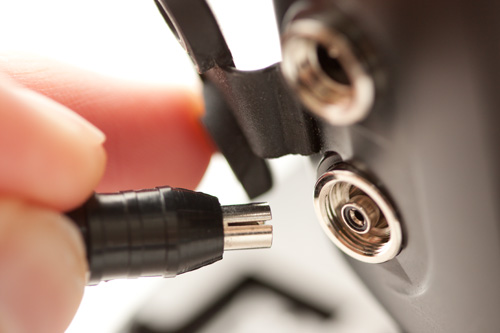 PC sync cord male connector being plugged into the female socket on flash