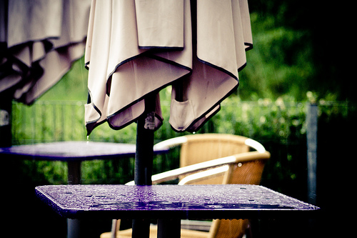 empty cafe tables in the rain