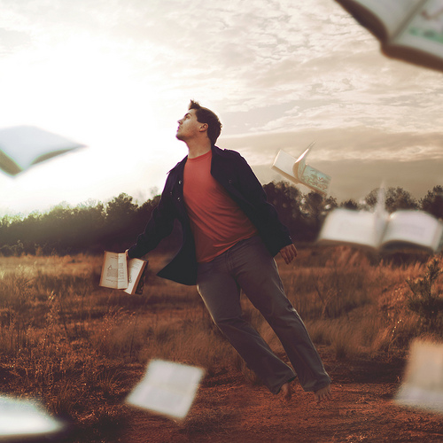 Man floating in whirlwind with books flying around him