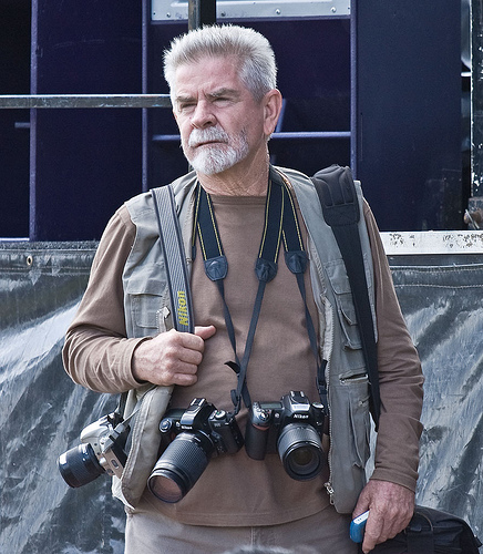 Photographer with multiple cameras hanging from straps