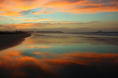 Sunset reflected in the wet sand at Ohope Beach, New Zealand