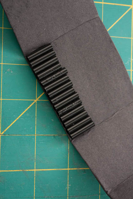 Card covered in black paper with a row of 2 cm black straw sections glued to it