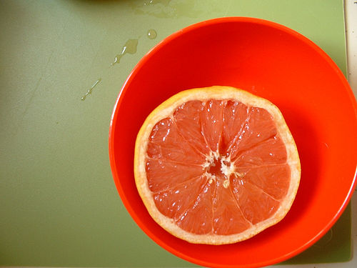 Red bowl with grapefruit on a green chopping board - example of using complementary colors to create color contrast