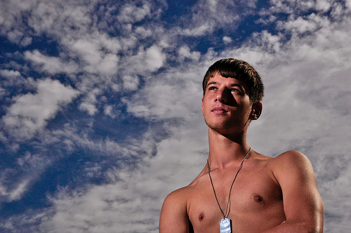 Swimmer portrait, neutral density filter, fast shutter speed, and low ISO used to reduce effect of ambient light (sunlight) and darken background. Speedlight flash fired at full power as main light.