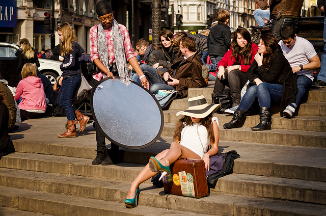 Assistant holding a reflector next to a model for a photo shoot