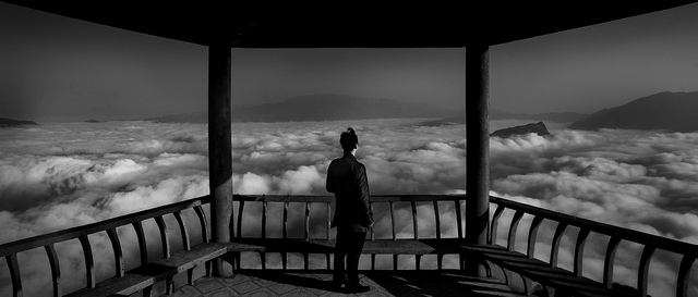 Man standing in pagoda overlooking a sea of clouds, taken as part of a photography challenge