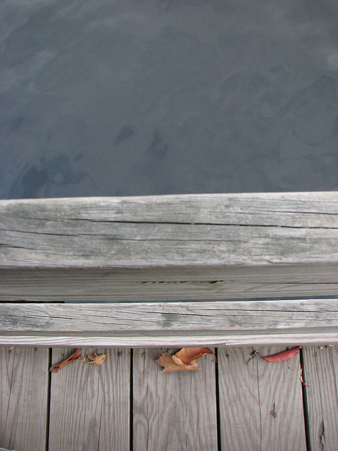 Close-up of the edge of a wooden walkway over water, abstracted into shapes