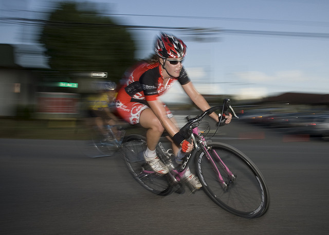 Cycle race photographed using a slow shutter speed and rear curtain sync flash. The blur of the moving riders stretch behind them, giving a feel of forward movement.